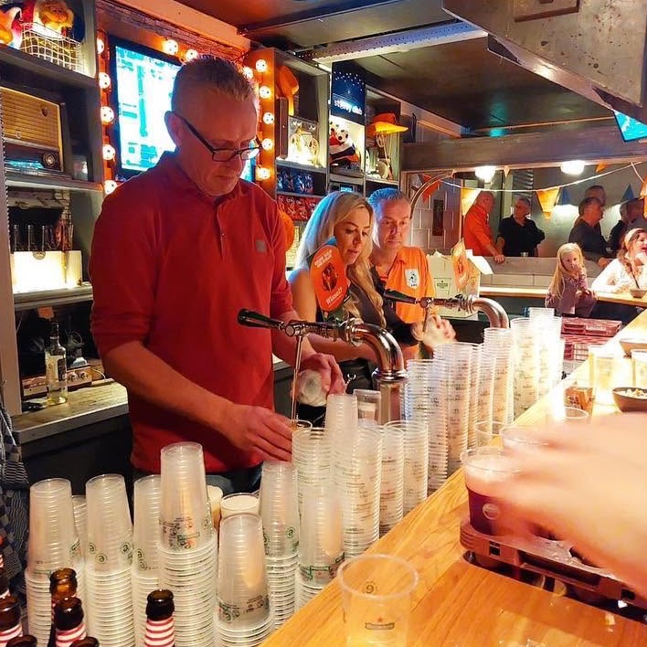 Vrijwilligers tappen bier achter de bar