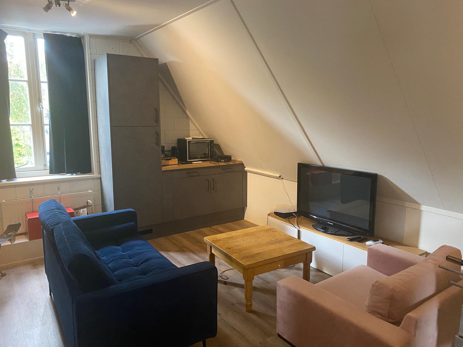 De zithoek van het internetcafé met banken, een salontafel en een televisie